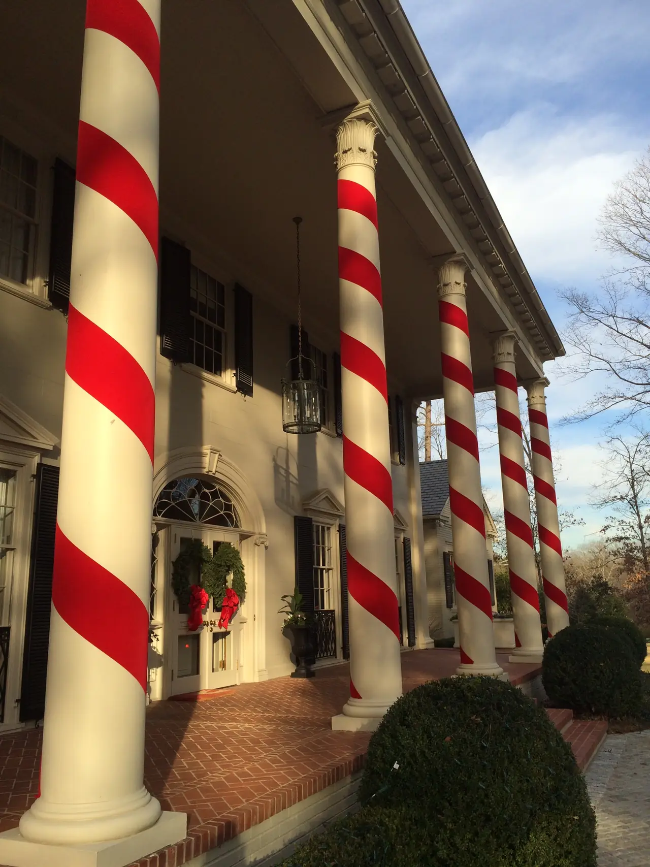 Tall porch columns are wrapped in red and white candy-cane stripes.