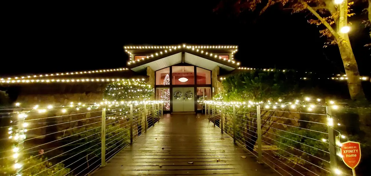 Lights follow a wooden walkway and roofline toward a decorated entrance.