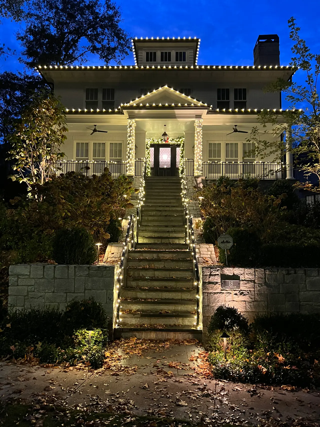 Lit garland lines a long stairway leading to a home at blue hour.